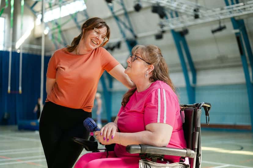 A smiling woman who uses a wheelchair chatting with a support worker at a community centre