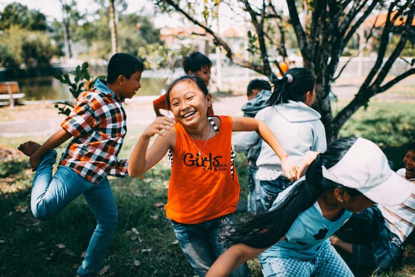 A group of children laughing and running together outdoors